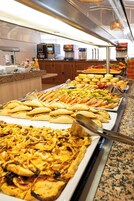Un bufé con distintos alimentos, incluyendo quesadillas, ensaladas y un gran plato de pollo.