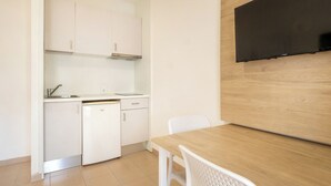 A compact kitchen with white cabinets, a dishwasher, and a wooden dining table with two chairs. - Cabot Club Torre Blanca (Sant Llorenc des Cardassar)