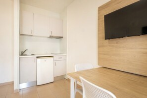 A compact kitchen with white cabinets, a dishwasher, and a wooden dining table with two chairs. - Cabot Club Torre Blanca (Sant Llorenc des Cardassar)