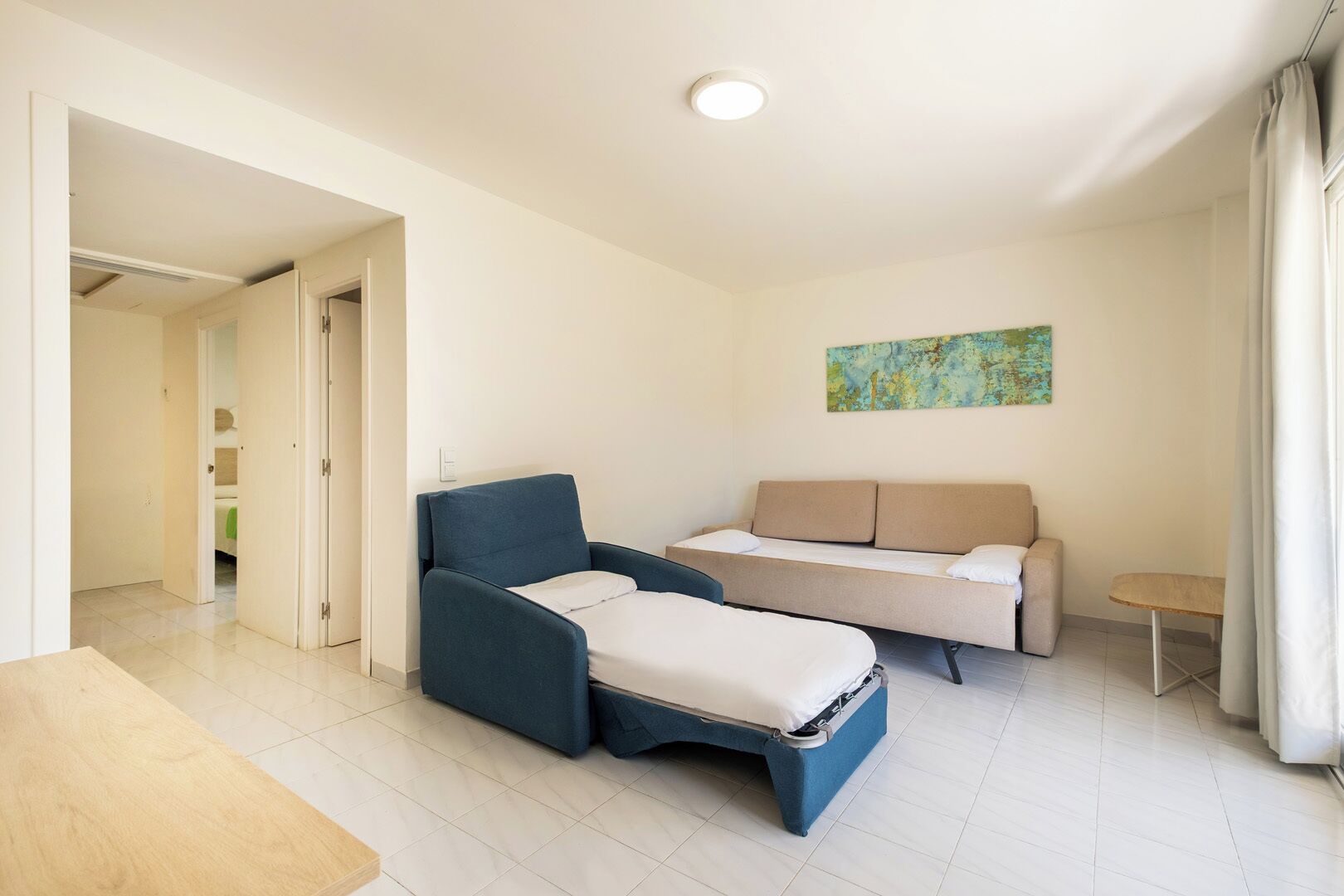 Una habitación moderna con un sofá, una silla, una mesita y un cuadro en la pared.