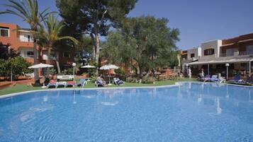 Una piscina al aire libre, sombrillas, tumbonas