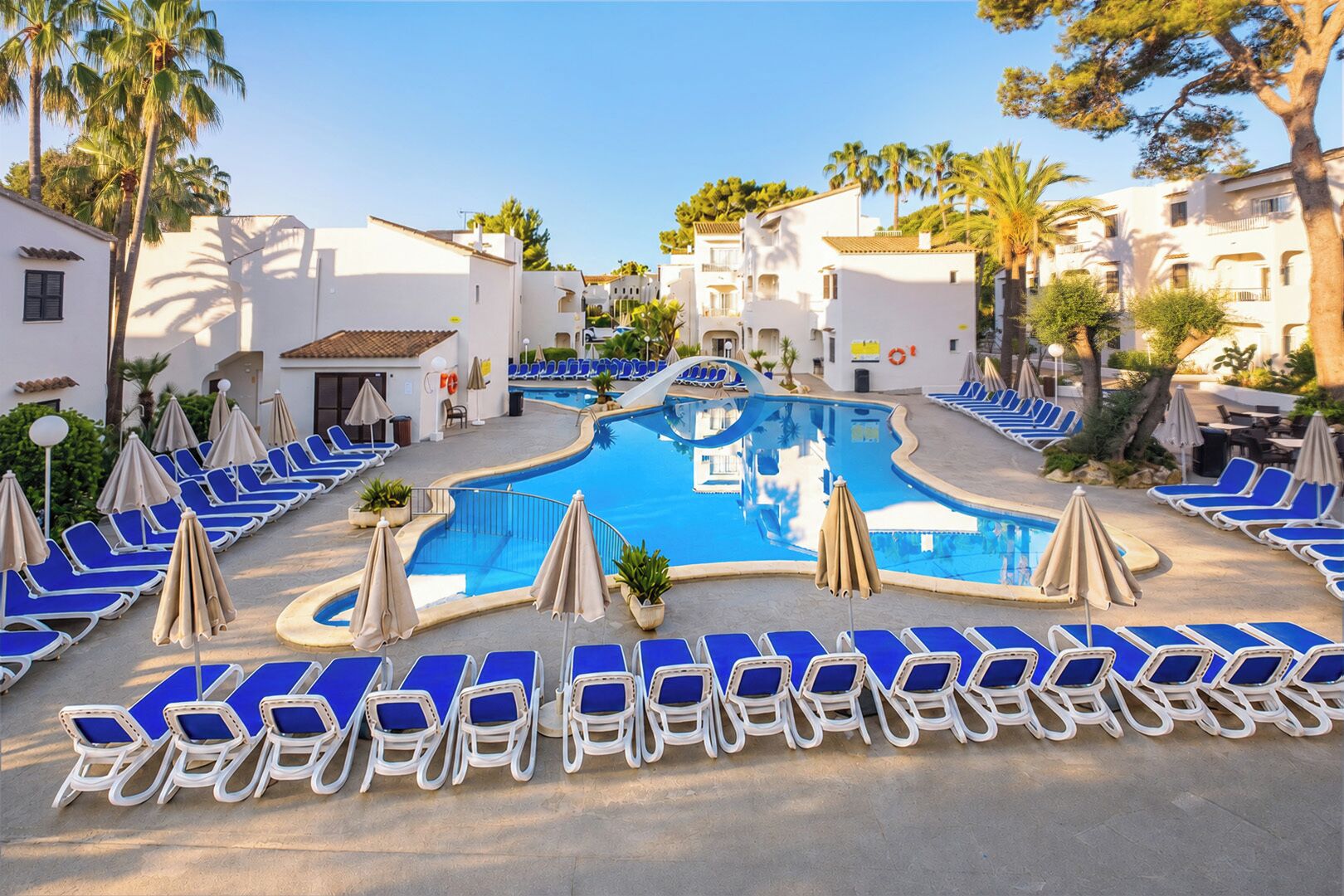 A pool area with lounge chairs and umbrellas, surrounded by buildings.