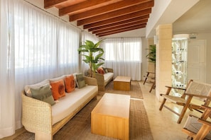 A living room with a sofa, coffee table, and chairs, a large plant, and a glass display cabinet. - Cabot Club Torre Blanca (Sant Llorenc des Cardassar)