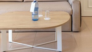 A room with a beige sofa, a wooden coffee table with a bottle and glasses, and a colorful abstract painting on the wall. - Cabot Club Torre Blanca (Sant Llorenc des Cardassar)