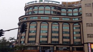 A multi-story building with a curved facade, featuring large windows and a prominent sign at the top.