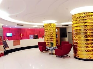A lobby with a reception desk, red chairs, and a yellow pillar. - Jinjiang Inn Style (Huizhou West Lake Park DongZhan Store) (Huizhou)
