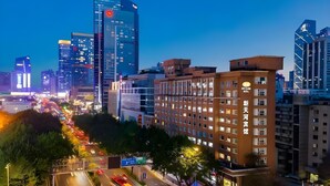 A cityscape with modern high-rise buildings, a multi-story hotel, and a busy street with traffic. - Ausotel New Tianhe Guangzhou (Guangzhou)