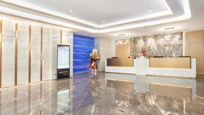 A modern hotel reception area with a marble floor, a reception desk, a digital information board, and a blue accent wall. - Ausotel New Tianhe Guangzhou (Guangzhou)