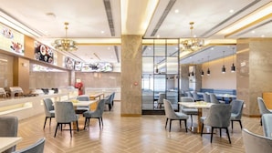 A modern restaurant with a bar area, seating with tables and chairs, and a view through a glass wall. - Ausotel New Tianhe Guangzhou (Guangzhou)