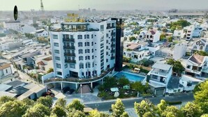 A multi-story hotel with a rooftop pool, surrounded by residential buildings.