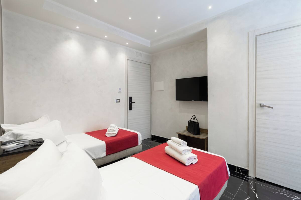 A hotel room with two beds, a TV, and a wardrobe.