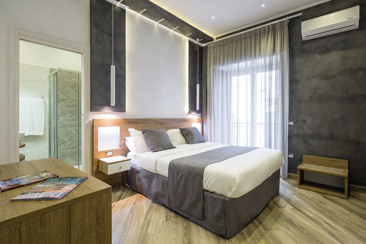 A modern hotel room with a large bed, bedside tables, a wooden bench, and a magazine on the side table.