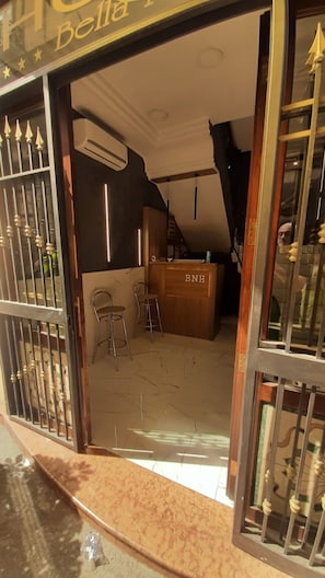 A hotel entrance with a reception desk labeled 'BNH,' a staircase, and a bar area. - Hotel Bella Napoli (Naples)