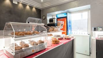 Una vitrina de panadería con diversos productos horneados y una máquina de café.