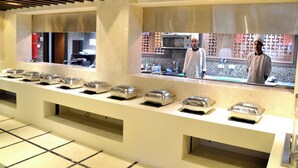A buffet setup with covered food containers and a kitchen area in the background.