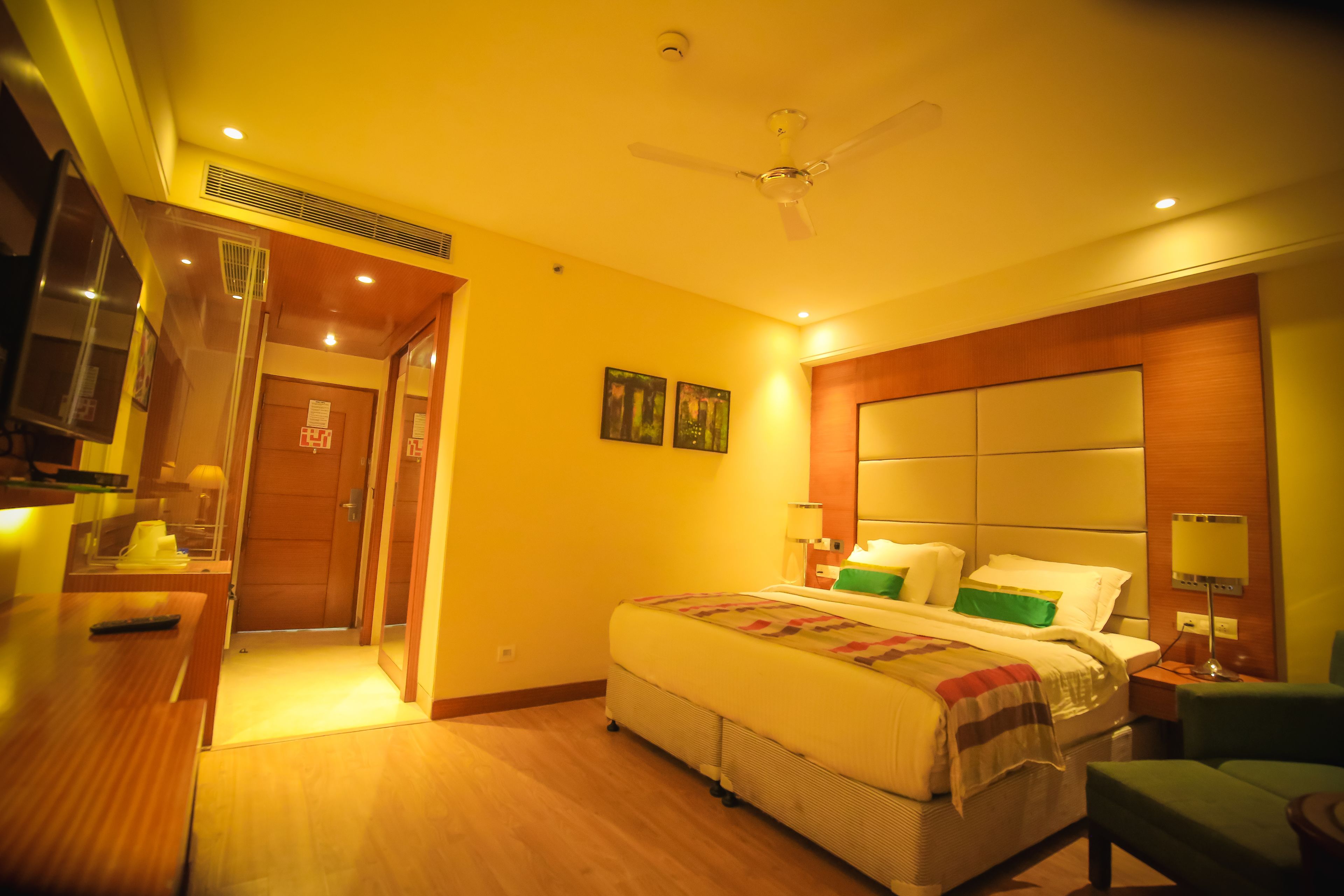 A hotel room with a bed, bedside table, nightstand, lamp, and a ceiling fan.