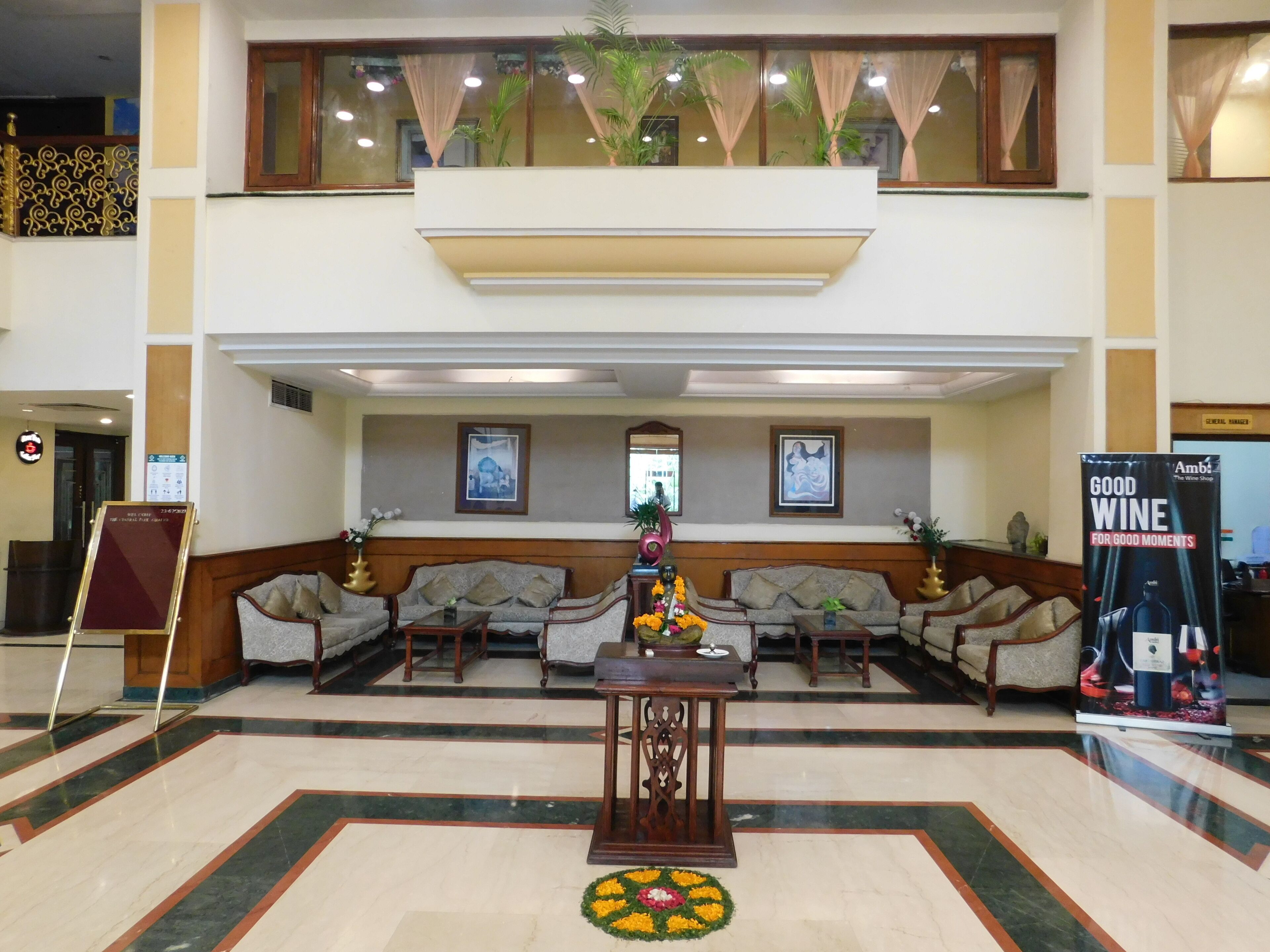 A hotel lobby with a reception desk, seating area, and a sign promoting wine.