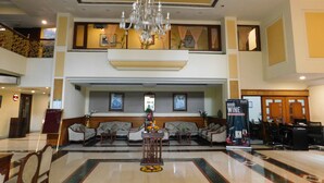 A lobby with a chandelier, seating area, and a reception desk.