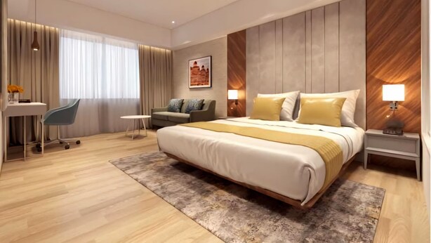 A modern hotel room with a large bed, a desk, a sofa, and a small table.