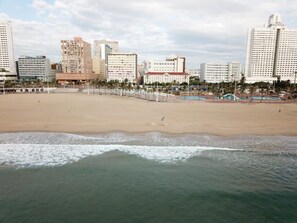 A beach with a cityscape in the background, including tall buildings and palm trees. - Balmoral (Durban)