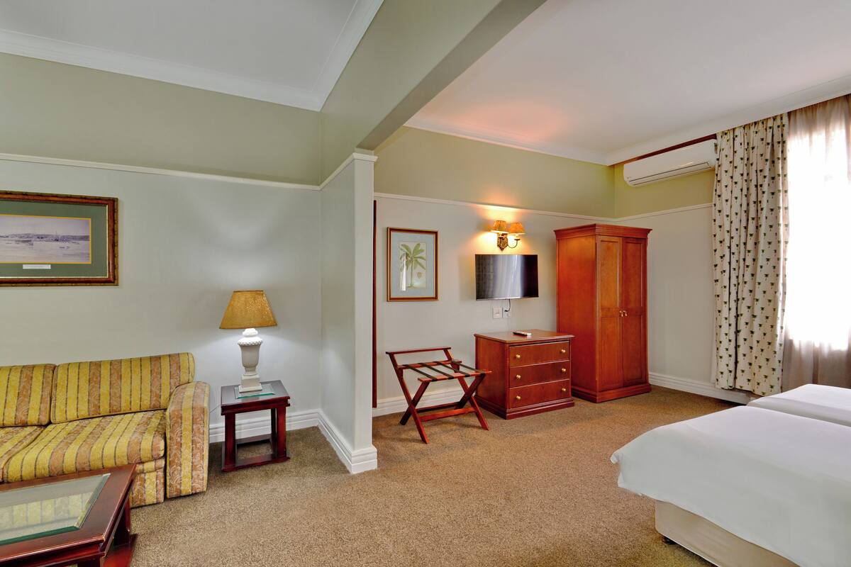 Una habitación de hotel con sofá, escritorio, armario, cama y televisor.