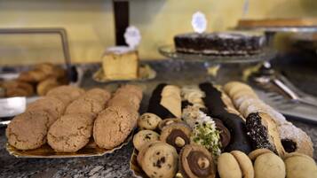 Une variété de desserts étaient exposés, notamment des biscuits, des confiseries enrobées de chocolat et un gâteau présenté sur un plateau de service.