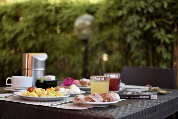 Una mesa dispuesta para el desayuno, con huevos, jamón y una bebida, además de un libro y unas llaves.