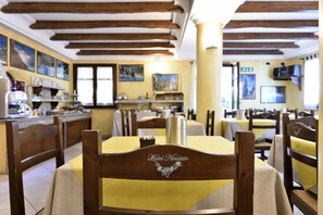 A restaurant with wooden beams on the ceiling, yellow tablecloths, and wooden chairs. - Nicoletta Hotel (Baunei)