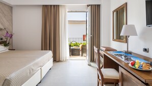 A hotel room with a bed, desk, chair, and a balcony with outdoor furniture. - Nicoletta Hotel (Baunei)