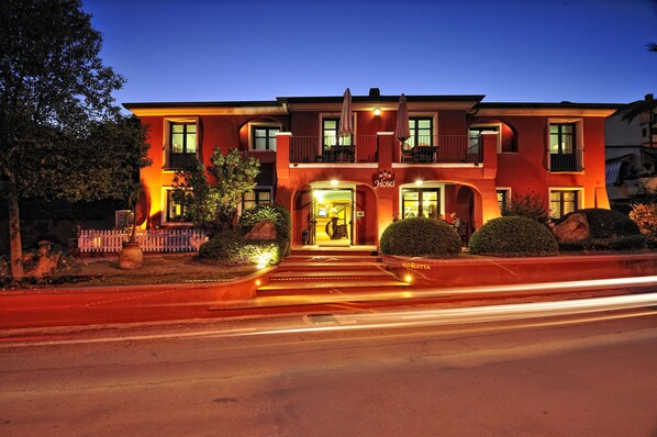 A hotel with a grand entrance, multiple balconies, and a well-lit facade. - Nicoletta Hotel (Baunei)