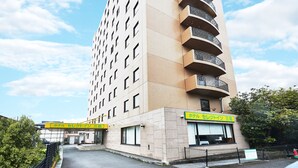 A tall hotel with a modern design, featuring a prominent entrance and a sign in a foreign language. - HOTEL KAN-RAKU Mishima Main Street (Mishima)
