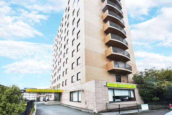 A tall hotel with a modern design, featuring a prominent entrance and a sign in a foreign language.