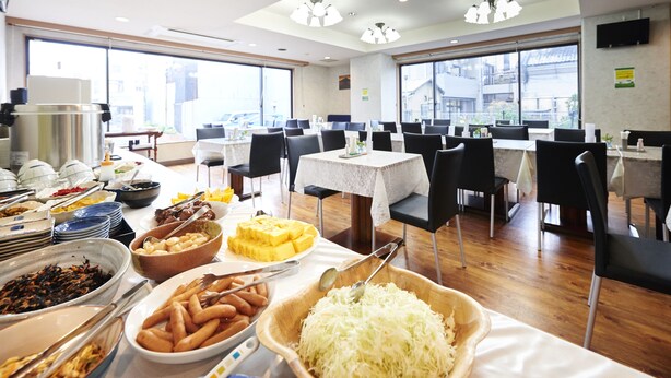 A buffet setup with various food items and a dining area with tables and chairs. - HOTEL KAN-RAKU Mishima Main Street (Mishima)