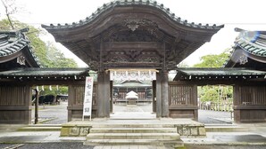 Um portão japonês tradicional com intrincados trabalhos em madeira e um emblema central.