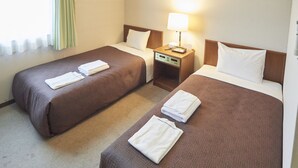 Quarto de hotel com duas camas, cada uma com colcha marrom e almofadas brancas. Há uma mesa de cabeceira com abajur e telefone entre as camas.