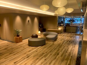 A modern interior with wooden flooring, a reception desk, and seating areas.