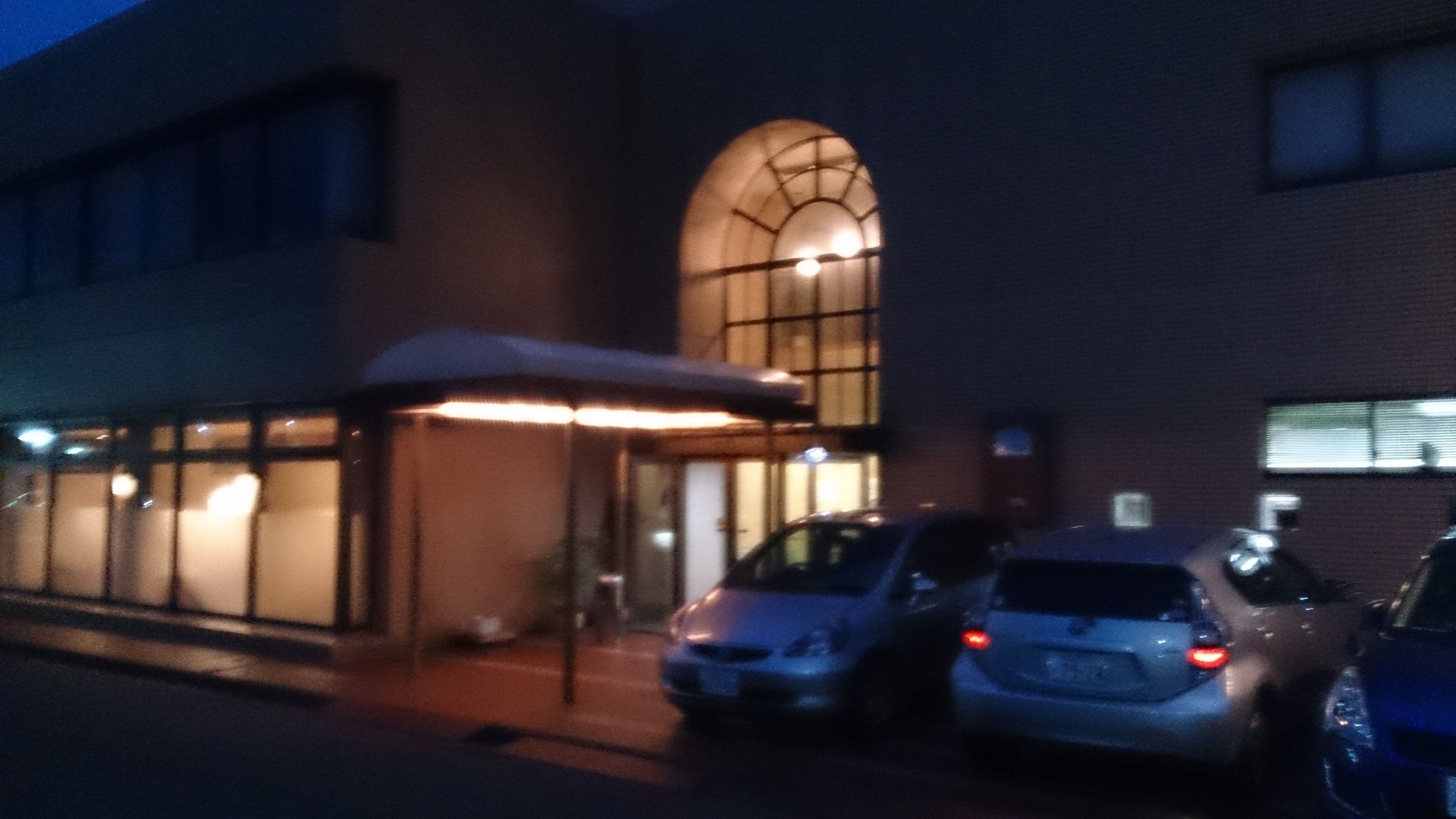 Een gebouw met een overdekte ingang en geparkeerde auto's.