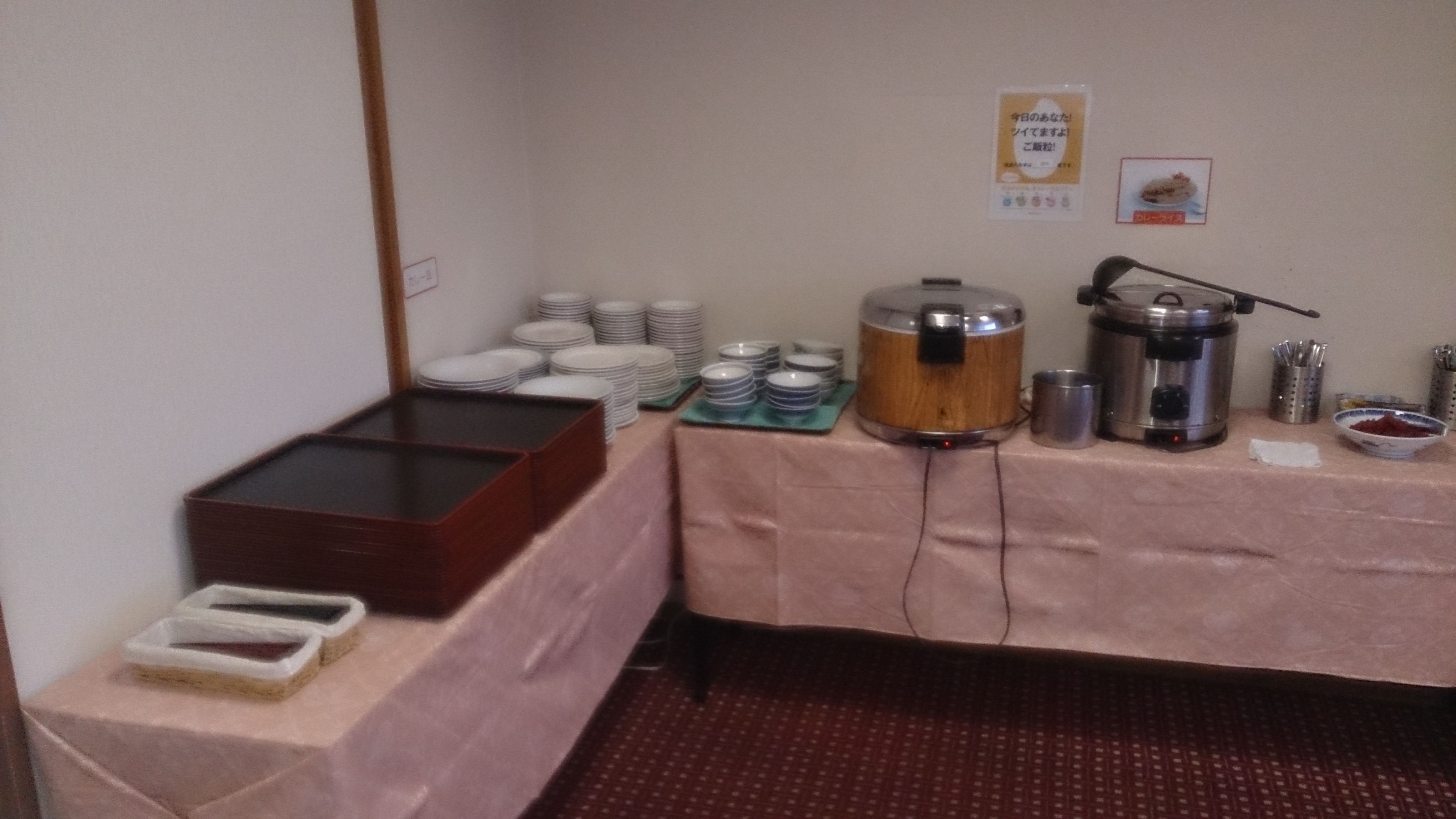 Montaje de bufé con platos apilados, una cafetera y un recipiente para alimentos.