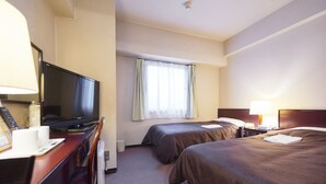 Une chambre d’hôtel équipée d’une télévision, de deux lits, d ’un bureau avec une lampe et d’une fenêtre avec des rideaux.