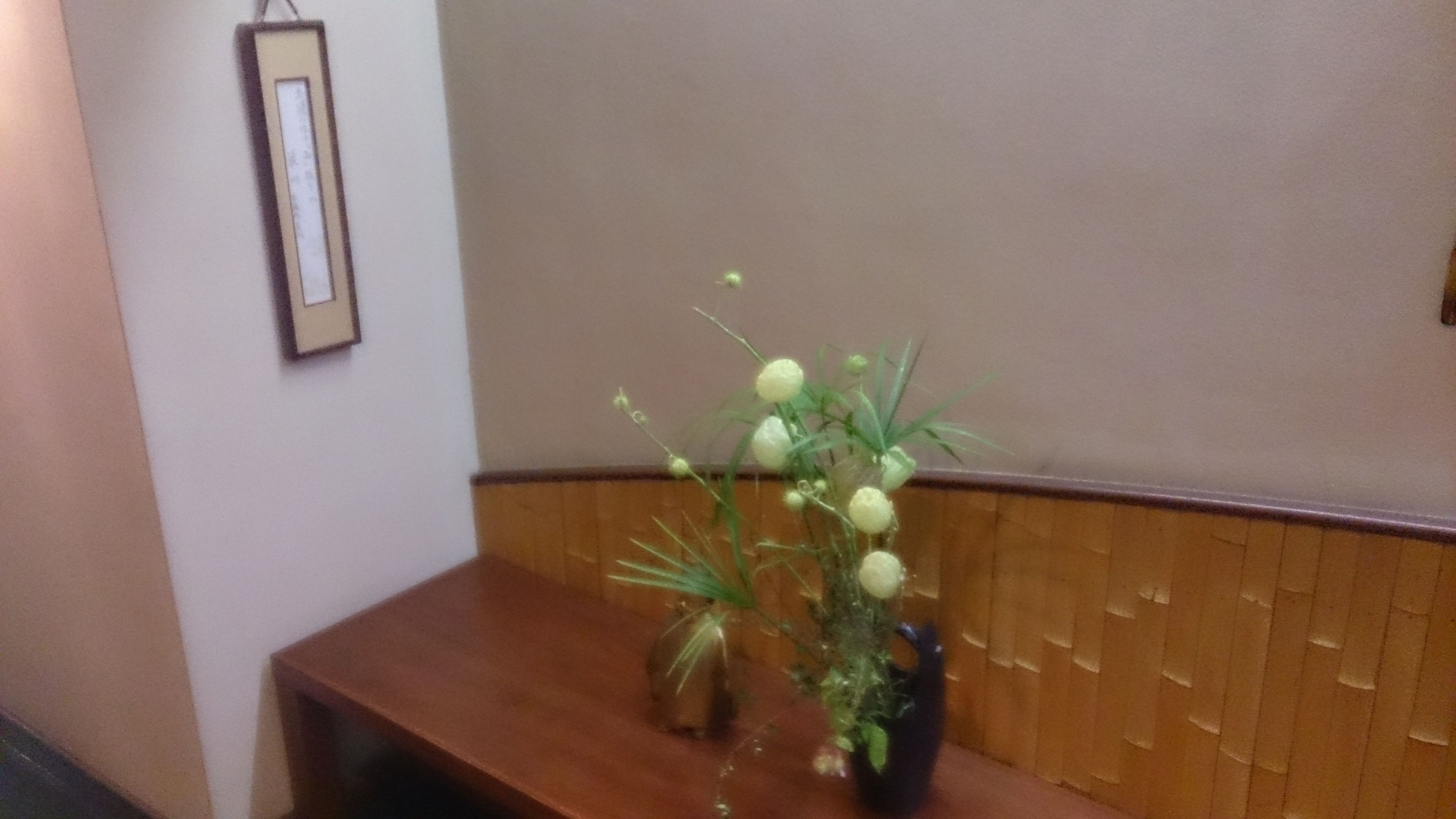 A wooden bench with a vase of white flowers.