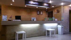 Un comptoir d’accueil avec une pancarte indiquant « SERVICE D’INFORMATION » et un mur de briques en arrière-plan.
