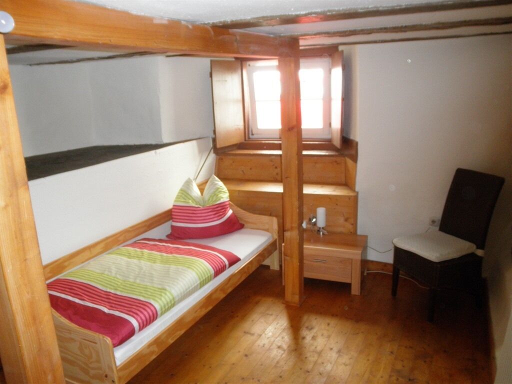 A small, cozy room with a bunk bed, a desk, and a chair.