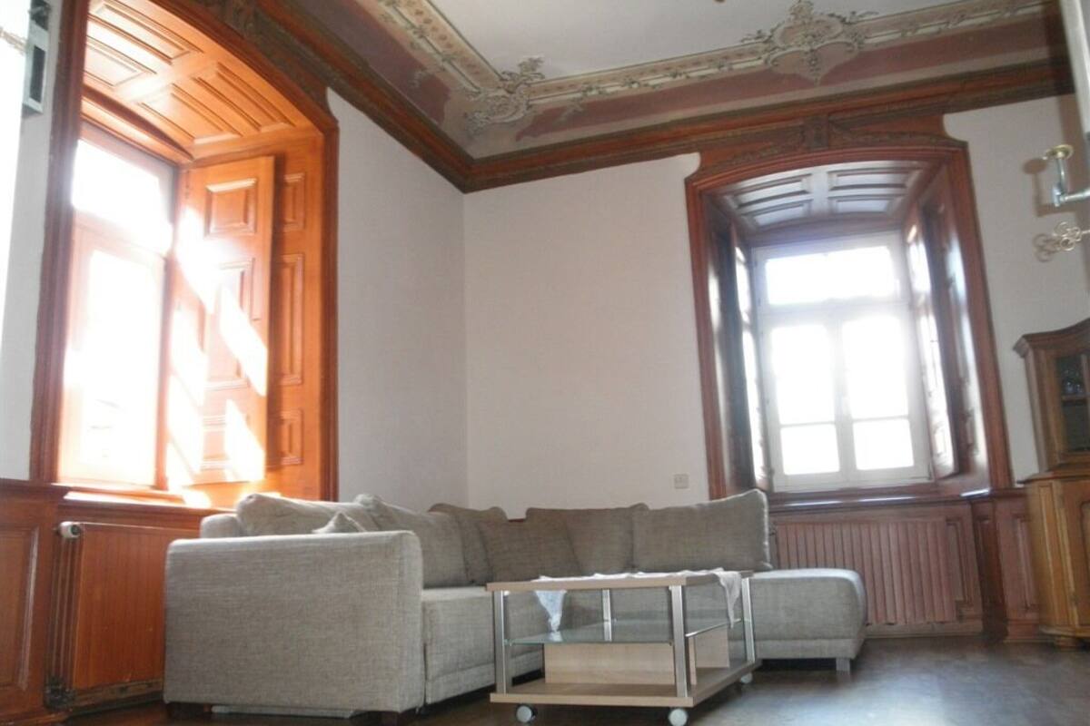 A room with a wooden ceiling, a large window, a sofa, and a small table.