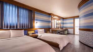 Una habitación de hotel con dos camas, un tocador con espejo y una pequeña cocina.