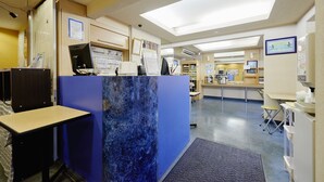 A reception area with a blue marble counter, a computer, and a desk with a chair. - Hotel Select Inn Numazu (Numazu)