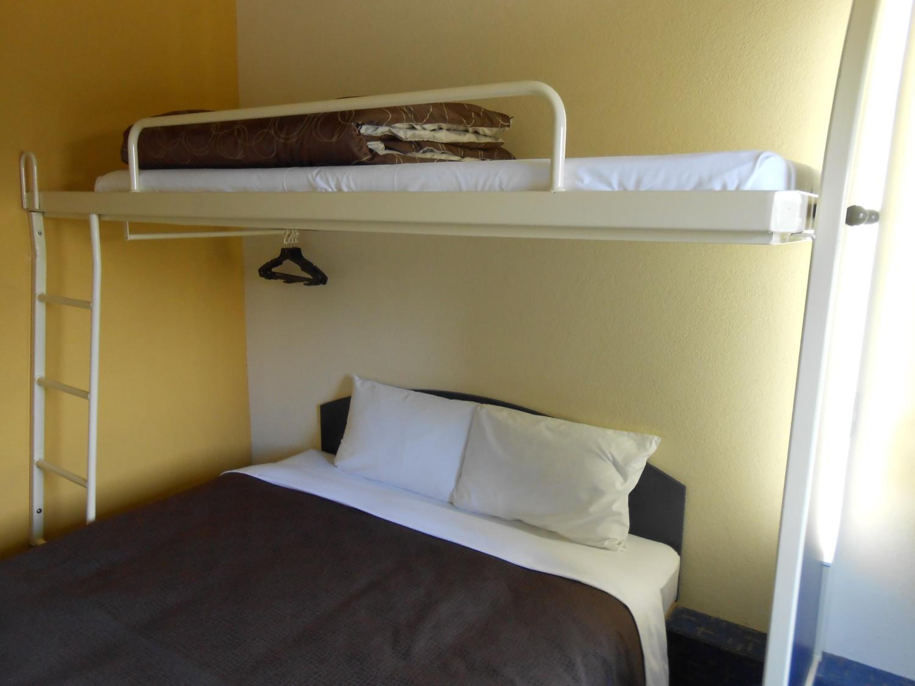 Een stapelbed met een ladder, een enkel bed beneden en een hangende kapstok.