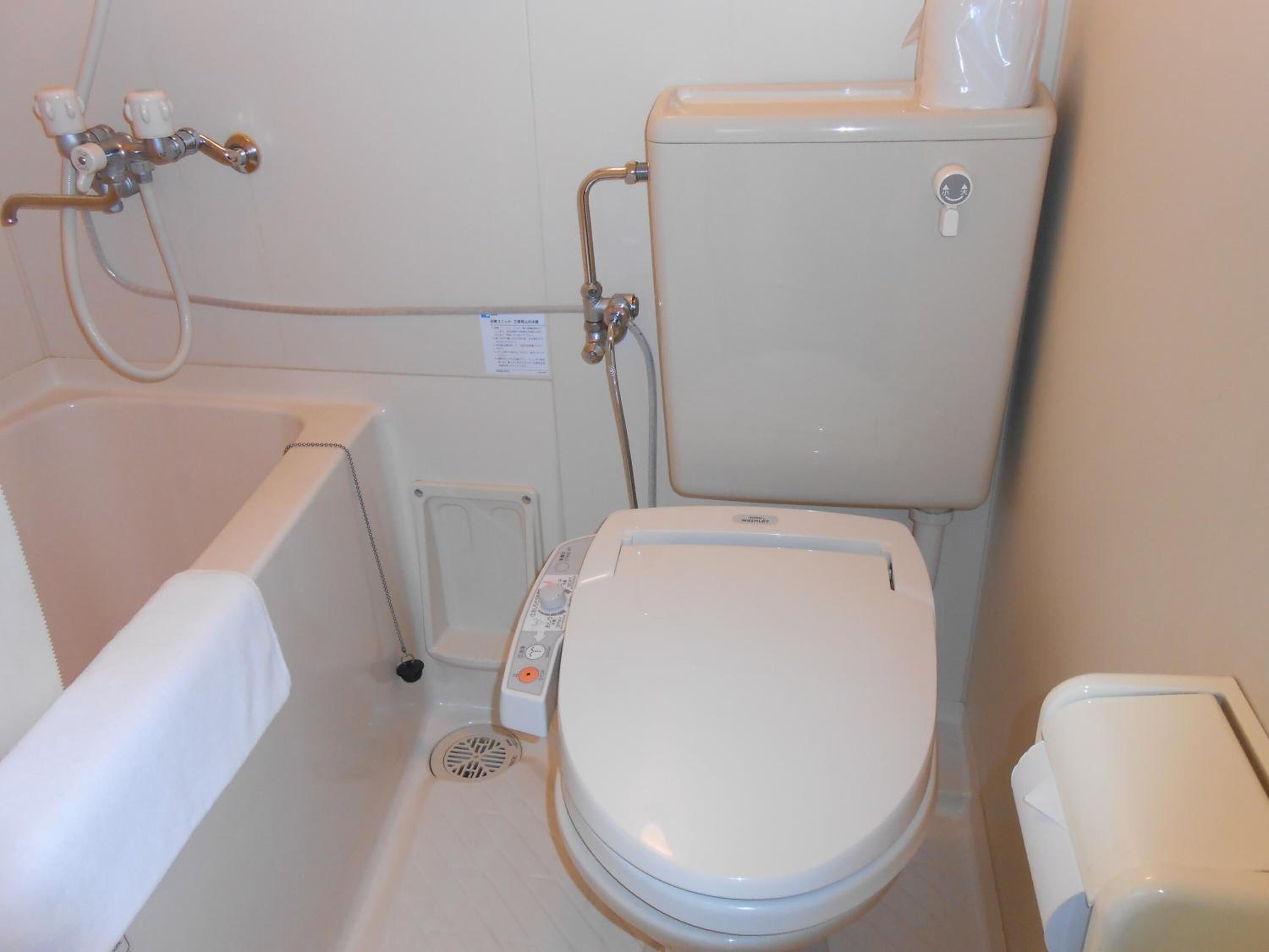 A bathroom with a bathtub, toilet, and a water heater.