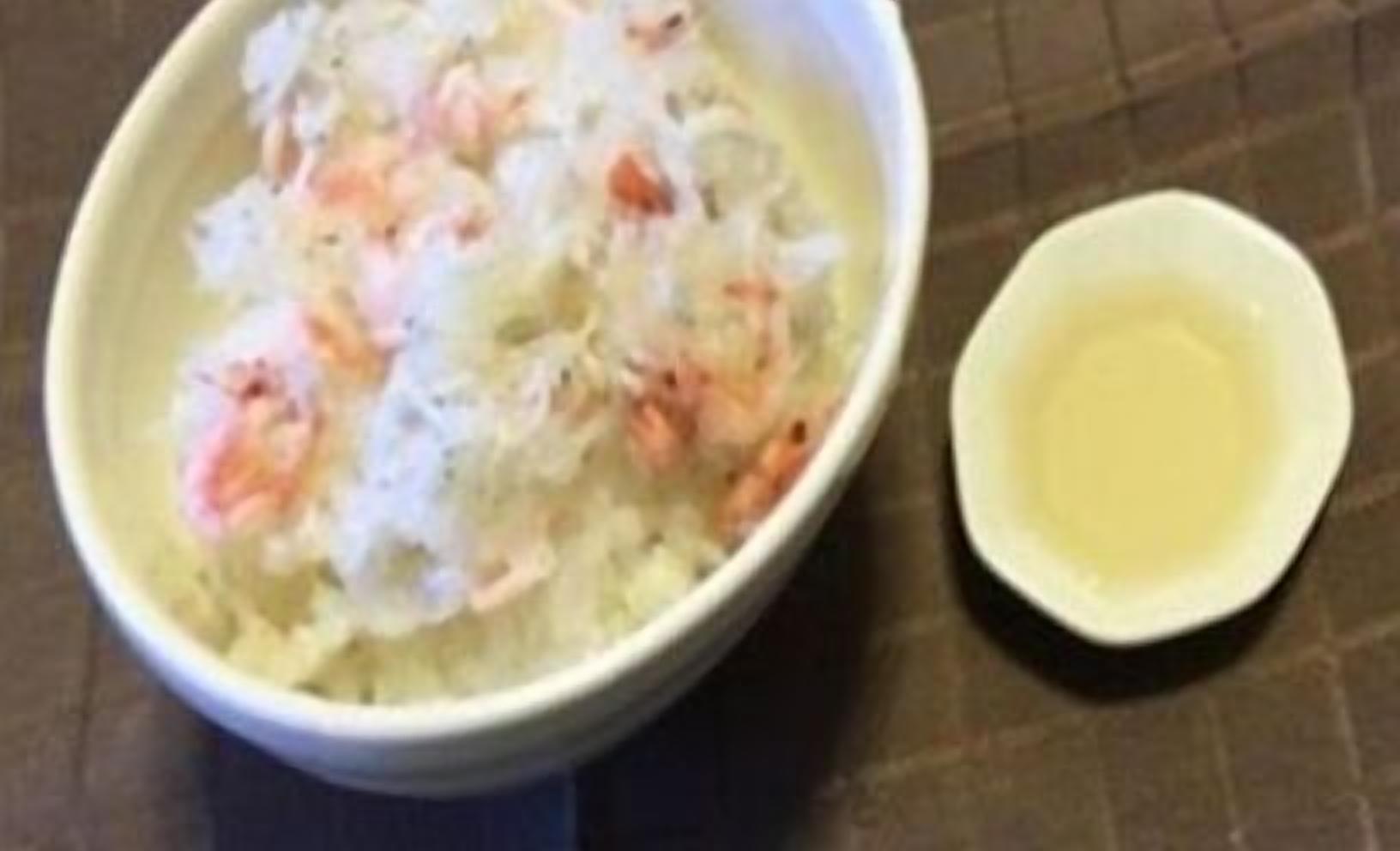 Un plato de arroz con camarones y un tazón pequeño de aceite.