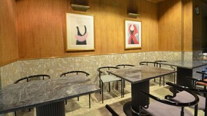 A restaurant with marble tables and chairs, framed artwork on the walls, and a clock on the wall. - Hotel Select Inn Nagoya Iwakura Ekimae (Iwakura)