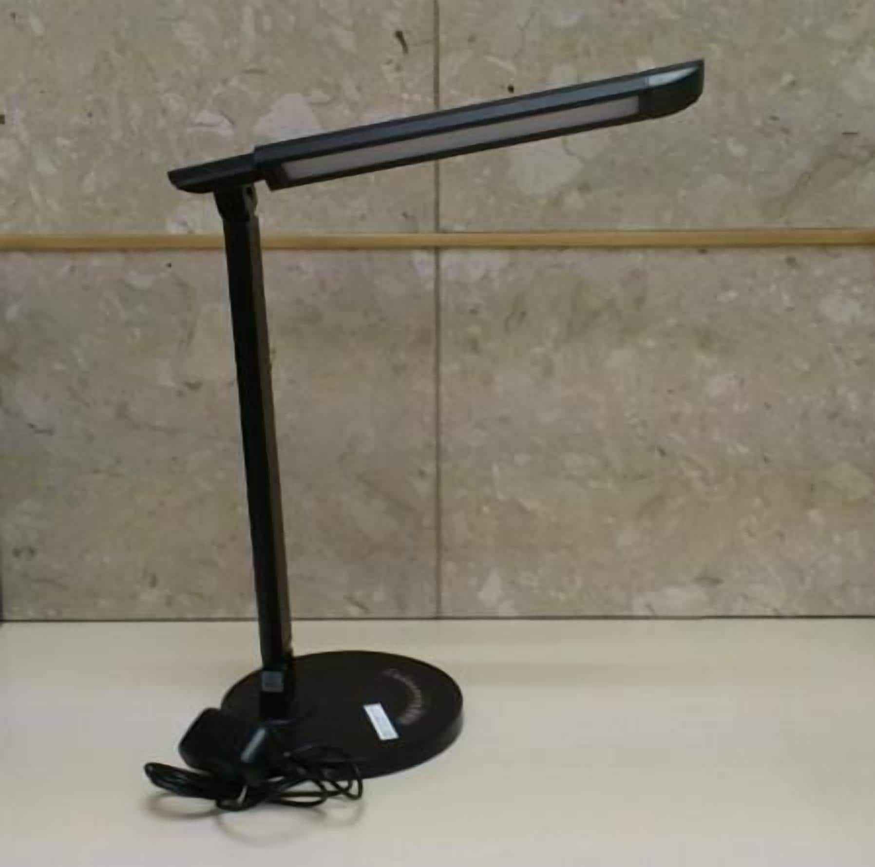 Eine schwarze Schreibtischlampe mit biegsamen Hals auf einer weißen Oberfläche.